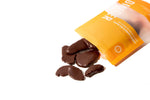The yellow Candied Ginger pouch lays on its side, with pieces of candied ginger spilling out.